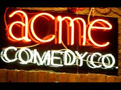 a neon sign that says acme comedy