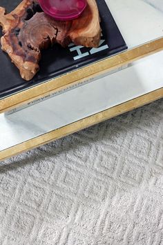 a glass coffee table with a red object on it's top and a wooden base