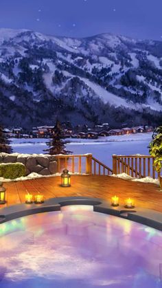 an outdoor hot tub with candles lit in front of a snowy mountain view at night