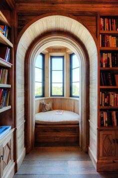 an arched window in the corner of a room with bookshelves on either side