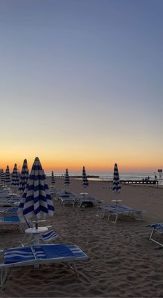 there are many beach chairs and umbrellas on the beach at sunset or sunrise time