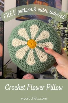 a crochet flower pillow is being held up