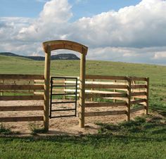 a wooden gate in the middle of a grassy field