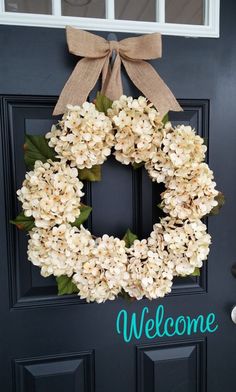 a wreath with the words welcome hanging on it's front door is decorated with hydrangeas