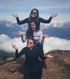 three women standing on top of a mountain