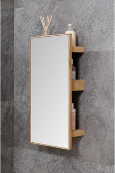 a mirror and shelf in a bathroom with grey marble wall behind it, next to a soap dispenser