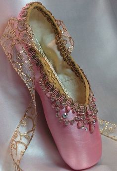 a pair of pink ballet shoes sitting on top of a white sheet