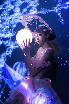 a woman in a pink dress holding a light up ball with blue lights behind her