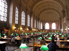 a large room filled with lots of tables covered in green lamps and bookshelves