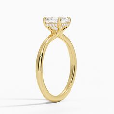 a yellow gold engagement ring with a pear shaped diamond in the center, on a white background