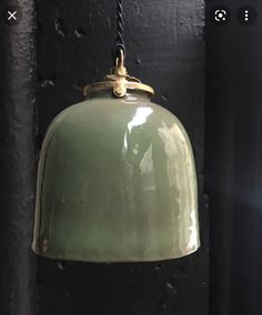 an old green light hanging from a black wall next to a lamp with a chain on it