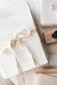 the wedding stationery is laid out on top of each other, with a rubber stamp