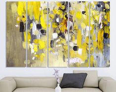 a living room with a couch and two paintings on the wall, one is yellow