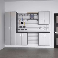 an empty garage with white cabinets and tools on the wall in front of black doors