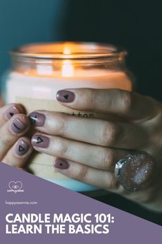 a woman holding a candle with her hands on top of it and two hearts painted on the nails