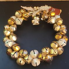 a close up of a bracelet made out of bells on a black surface with a leaf