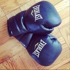 two black boxing gloves sitting on top of a wooden floor