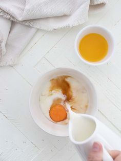 someone is mixing eggs in a bowl with milk and orange juices next to them