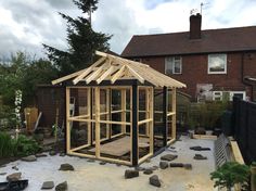 a small wooden structure in the middle of a yard with rocks and gravel around it