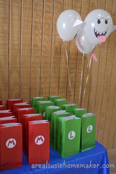 there are many bags on the table and balloons in the air above them that say super mario