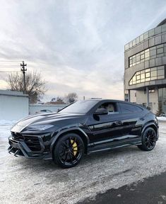 a black sports car parked in front of a building with snow on the ground next to it