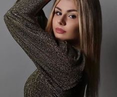 a beautiful young woman with long hair posing for a photo in front of a gray background