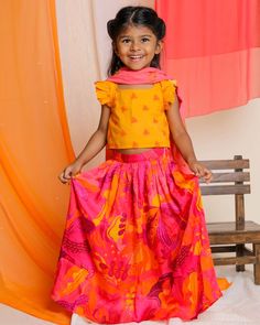 "Reminiscent of the flaming flowers of the Palash tree, the lehenga is printed in our signature hand-drawn print in bright shades of pink, yellow and orange. Made in gathered soft modal fabric (with pockets, of course the skirt has a flowy drape that falls beautifully with every twirl. It is paired with a mango yellow hand woven cotton blouse printed in our Bouin print. The sleeveless blouse has frills on the sleeves, and an adjustable tie-up at the back. The set is complete with a soft pink cot Summer Festive Lehenga With Printed Motifs, Festive Orange Floral Print Sets, Summer Floral Print Multicolor Lehenga, Summer Multicolor Floral Lehenga, Bohemian Orange Sets With Printed Motifs, Traditional Festive Sets With Vibrant Print, Multicolor Ikat Print Summer Sets, Summer Festive Ikat Print Sets, Festive Summer Ikat Print Sets