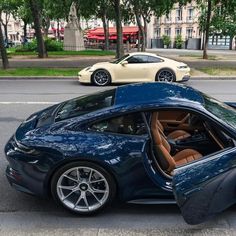 a blue sports car is parked on the side of the road with its door open