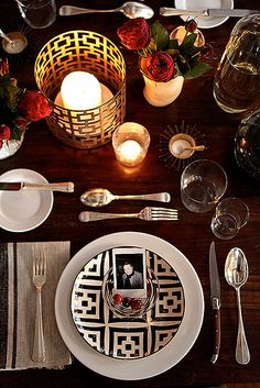 a table set with plates, silverware and candles