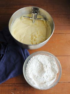 there is a bowl with flour in it next to another bowl on the table and a blue towel