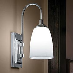 a wall light with a white shade on it in a bathroom area next to a mirror