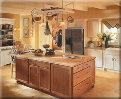 a large kitchen with an island in the middle and lots of hanging pots on it