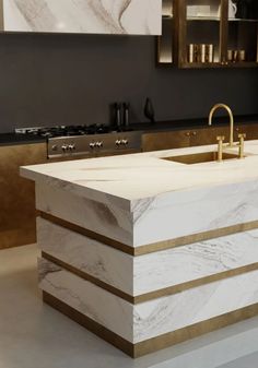 a modern kitchen with marble counter tops and gold faucets on the sink area