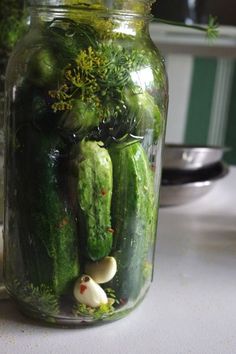 a jar filled with cucumbers sitting on top of a table