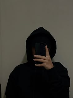 a person in a black hoodie holding a cell phone