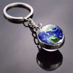 a keychain with the earth on it sitting on top of a black surface