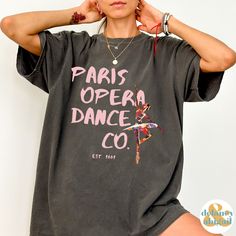 You will absolutely LOVE this trendy Paris Opera Dance Company Ballet Shirt. The perfect gift for the dancer in your life. Comfort Colors introduces the soft-washed, 100% ring-spun cotton, garment-dyed fabric that brings extra coziness to your wardrobe while the relaxed fit makes it an excellent daily choice. The double-needle stitching throughout the tee makes it highly durable while the lack of side-seams helps the shirt retain its tubular shape.  ❤ The Comfort Colors 1717 tee is made with medium fabric (6.1 oz/yd² (206.8 g/m      consisting of high quality, 100% ring-spun US cotton for long-lasting comfort. ❤ The relaxed fit keeps the wearer comfy in both casual and semi-formal settings      while the crew neckline delivers that classic, neat style which makes it perfect      for access Stretch Dancewear Tops For Dance Class, Fitted Tops For Dance Class, Stretch Tops For Dance Class, Black Dancewear Tops For Dance, Black Stretch Top For Dance Class, Stretch Black Top For Dance Class, Fitted Black Top For Dance Class, Graphic Print Short Sleeve Shirt For Dance, Short Sleeve Tops With Graphic Print For Dance Class