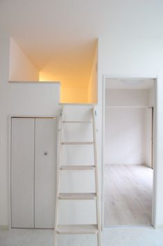 a ladder leaning against the wall next to a white cabinet and door in an empty room