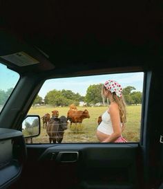 a pregnant woman in the back seat of a car looking at cows through a fence