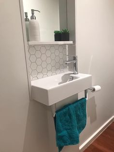 a white sink sitting under a bathroom mirror next to a green towel on a rack