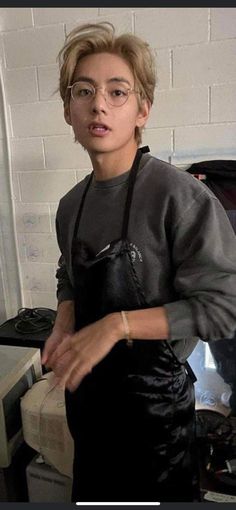 a young man wearing glasses and an apron