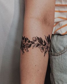 a woman's arm with flowers and leaves tattooed on the left side of her arm