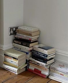 a stack of books sitting on top of a wooden floor next to a white wall