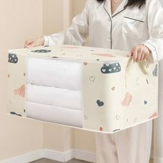 a woman is holding a box with sheets in it and she's wearing pajamas