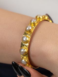 This beautiful piece is surrounded by lustrous pearls, evoking a sense of timeless beauty and sophistication. Crafted with care and attention to detail, this bracelet is sure to be an eye-catching addition to any ensemble. Whether you're dressing up for a special occasion or adding a touch of luxury to your everyday look, this bracelet is a must-have accessory. Treat yourself or someone special to this one-of-a-kind piece that exudes grace and style. Material: 22K Gold filled Brass, Adjustable b Pearl Bangle Bracelets For Anniversary, Pearl Bangle Bracelet For Anniversary, Anniversary Pearl Bangle Bracelet, Luxury Round Bracelets With Pearl Drop, Handmade Luxury Pearl Bracelet, Luxury Round Pearl Drop Bracelets, Luxury Pearl Drop Bracelet For Gift, Handmade Pearl Bracelet For Anniversary, Handmade Round Pearl Bracelet For Anniversary