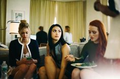 three women sitting on a couch eating food