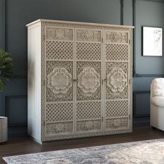 a white armoire sitting on top of a wooden floor next to a chair and rug