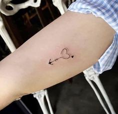 a woman's arm with an arrow and heart tattoo on the left inner arm