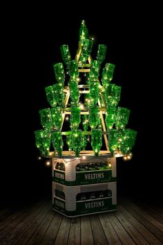 a lighted christmas tree made out of green wine bottles is on display in the dark