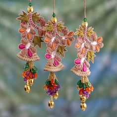 two pairs of earrings hanging from strings with colorful stones and beads on them, in front of a green background